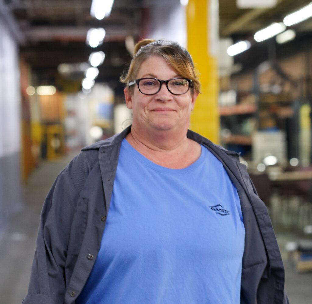 Woman with glasses in a blue shirt walking through the factory